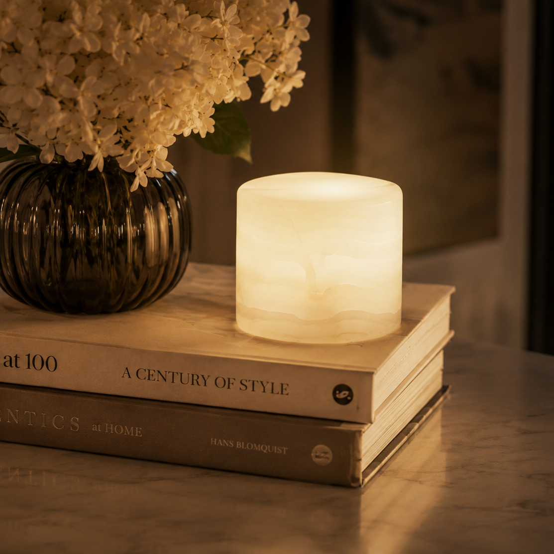 Lamp on books with a vase of flowers in the background