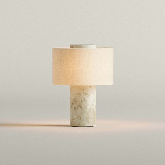 Table lamp with a beige shade and marble-like base on a light gray background