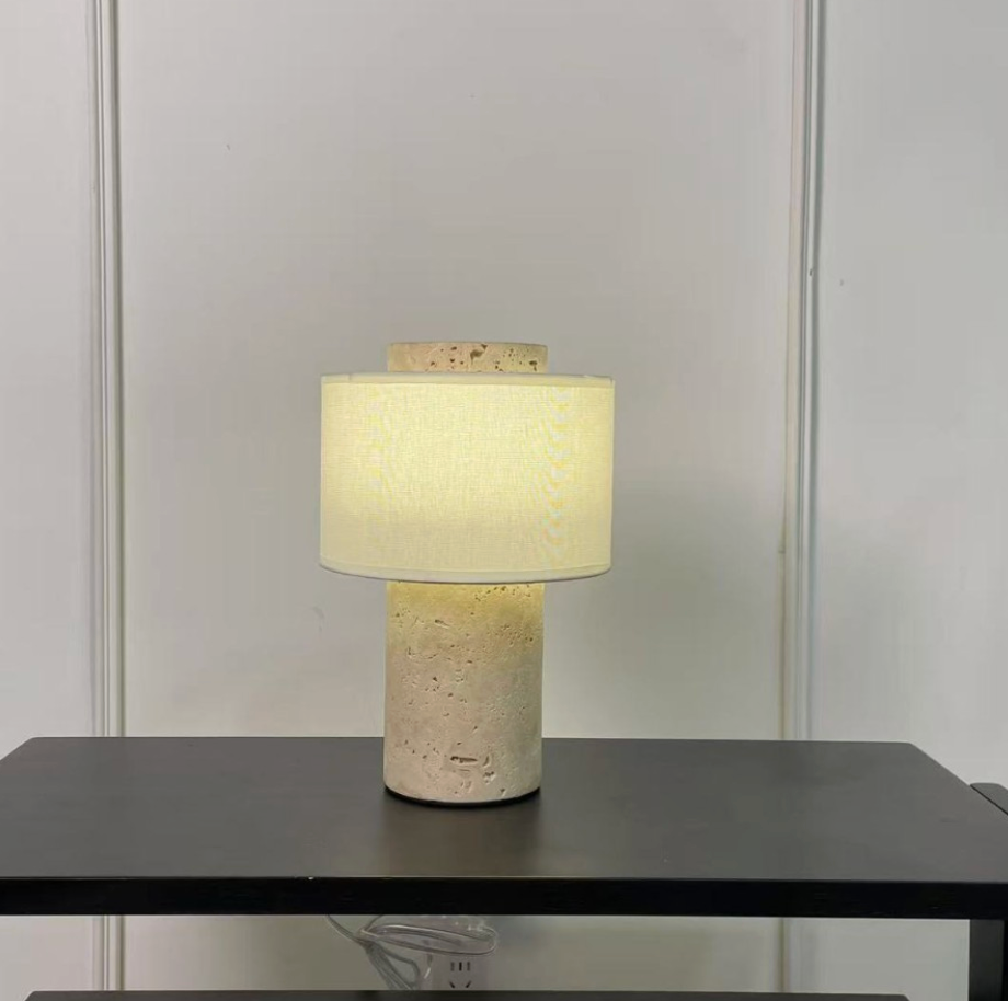 Table lamp with a textured base on a dark surface against a light gray wall